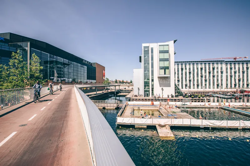 Ciclisti su un ponte pedonale lungo il porto di Copenaghen in estate
