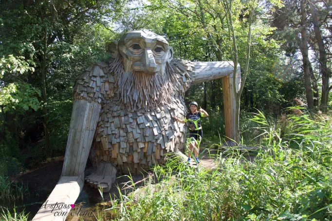 Ciclista accanto a un gigante di legno nascosto tra la vegetazione