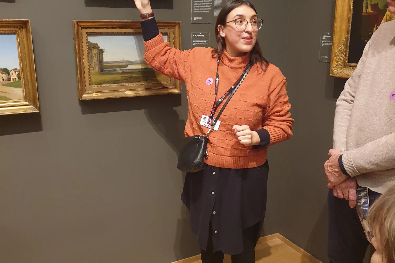 Guida con maglione arancione indica un dipinto allo Statens Museum for Kunst
