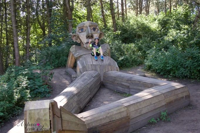 Ciclista seduto su un gigante di legno sdraiato nel bosco