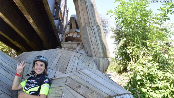 Ciclista posa sotto un ponte accanto al gigante di legno Oscar a Ishøj
