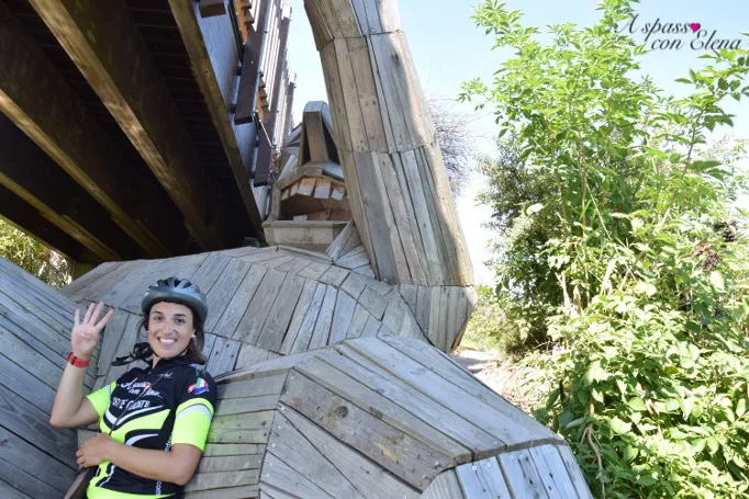 Ciclista posa sotto un ponte accanto al gigante di legno Oscar a Ishøj