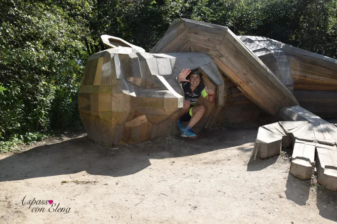 Bambino accovacciato dentro una grande scultura di legno di un gigante nascosto