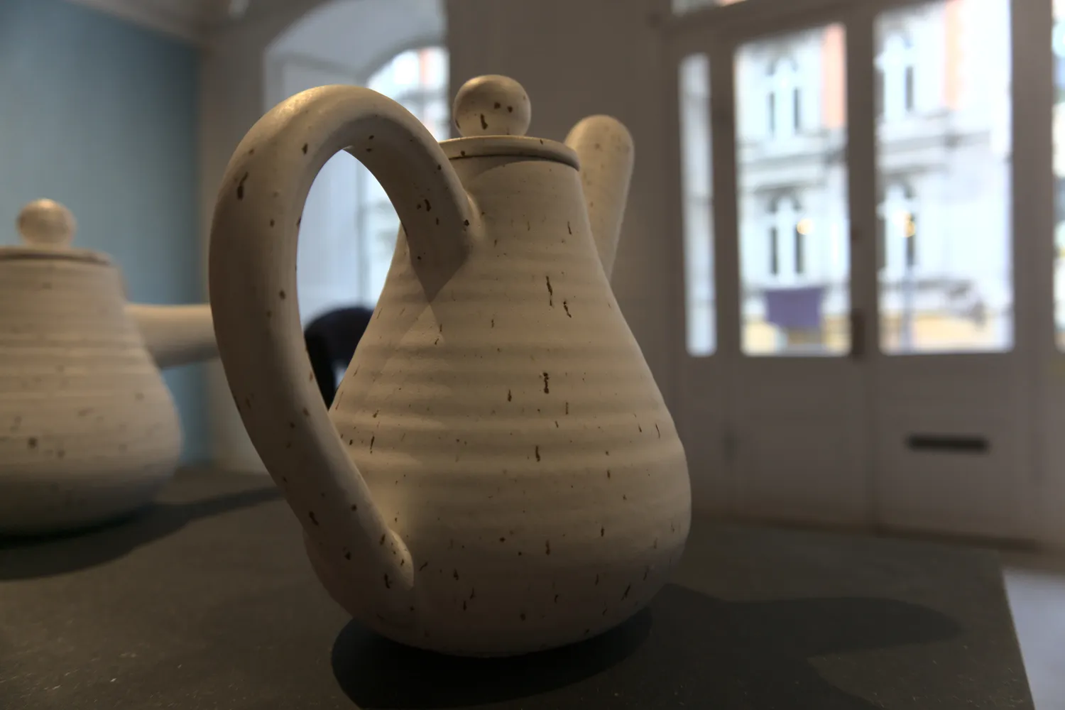 Caraffa di ceramica chiara con grande manico su un piedistallo museale