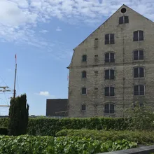 Antico magazzino in mattoni con alberi di una nave a vela accanto a un giardino