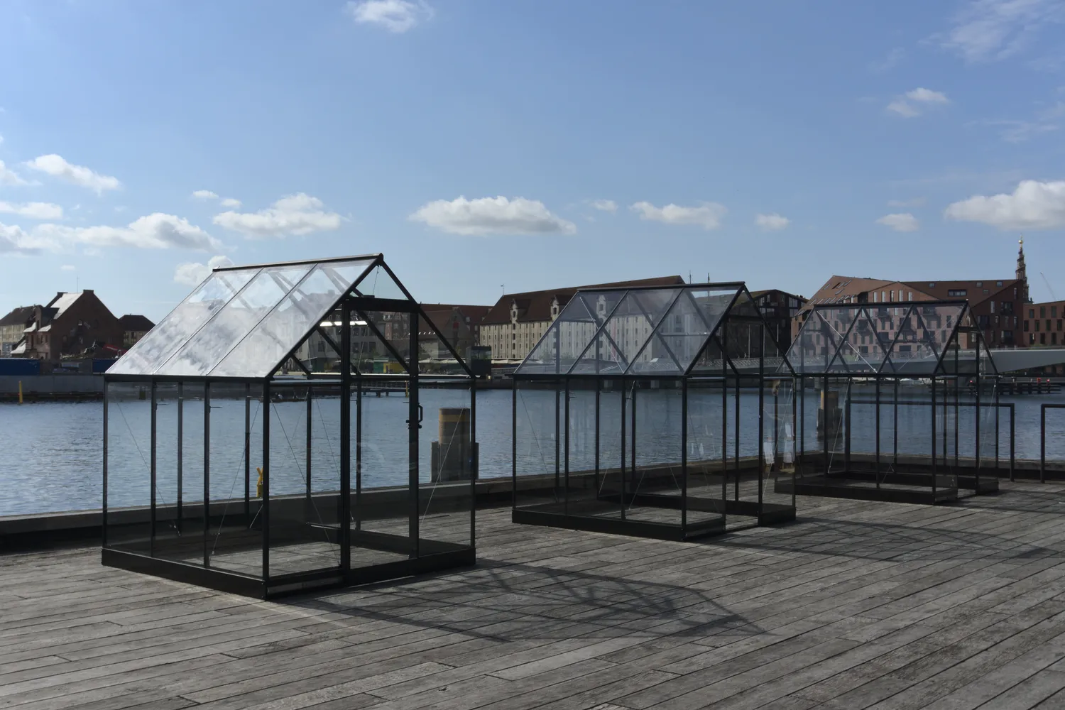 Serre in vetro e acciaio installate su un molo lungo il porto