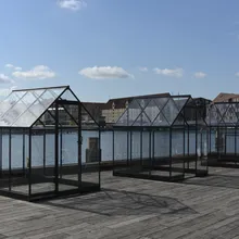 Serre in vetro e acciaio installate su un molo lungo il porto