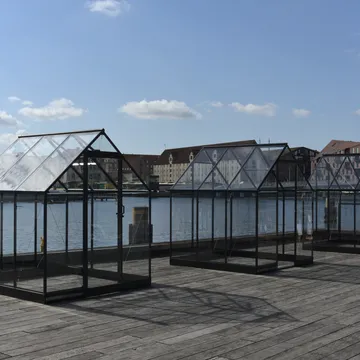 Serre in vetro e acciaio installate su un molo lungo il porto