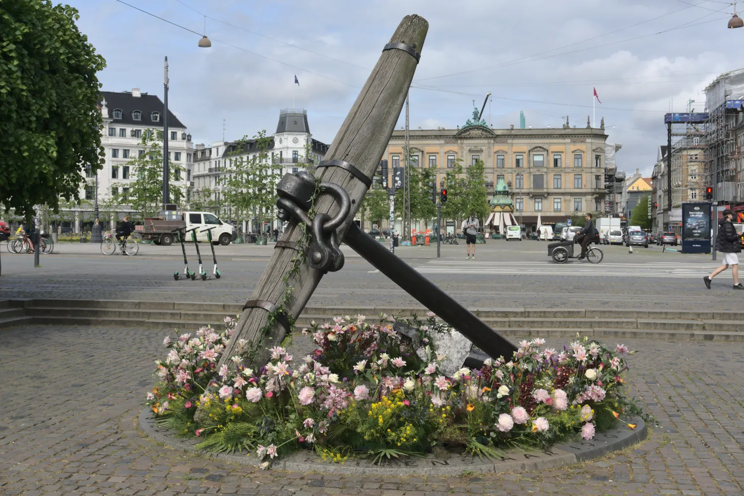 Grande ancora di legno e ferro circondata da fiori in una piazza