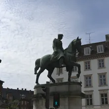 Statua equestre in bronzo davanti a un campanile e palazzi