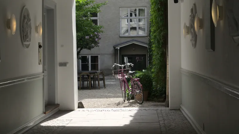 Cortile interno luminoso con bicicletta rosa visto da un androne