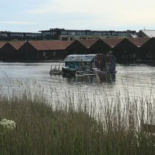 Casa galleggiante colorata su un canale a Christianshavn davanti a vecchi capannoni rossi