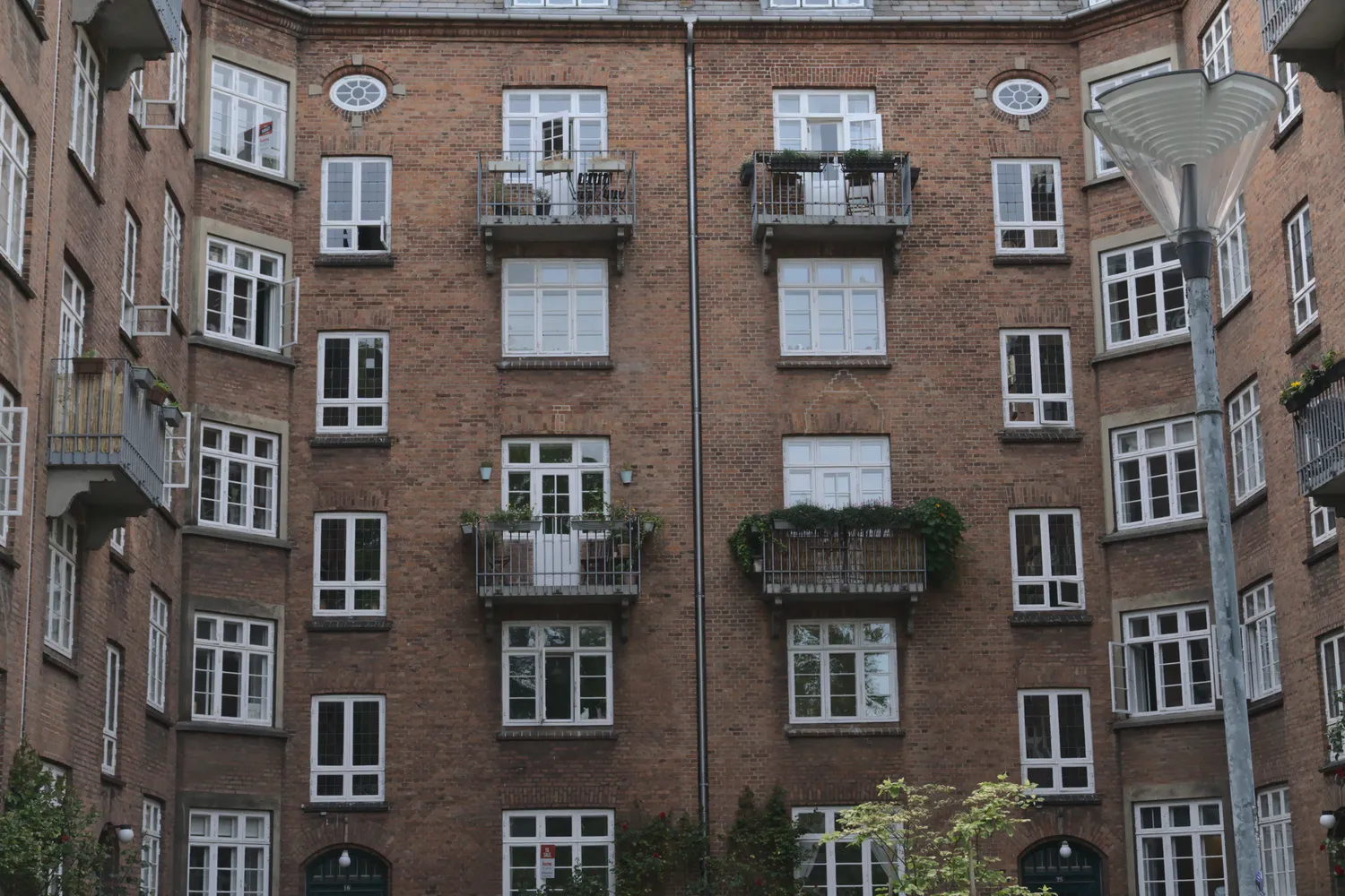 Cortile interno di un palazzo in mattoni con balconi e piante