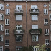 Cortile interno di un palazzo in mattoni con balconi e piante