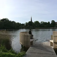 Pontile in legno sul lago con padiglioni circolari e una guglia sullo sfondo