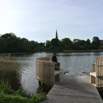 Pontile in legno sul lago con padiglioni circolari e una guglia sullo sfondo