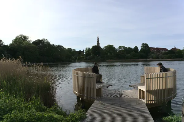 Pontile in legno sul lago con padiglioni circolari e una guglia sullo sfondo