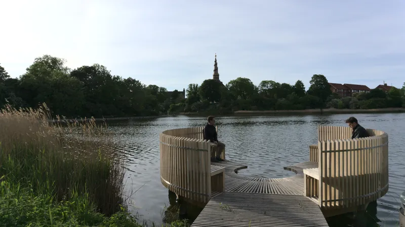 Pontile in legno sul lago con padiglioni circolari e una guglia sullo sfondo