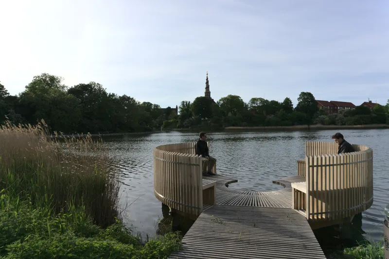 Pontile in legno sul lago con padiglioni circolari e una guglia sullo sfondo