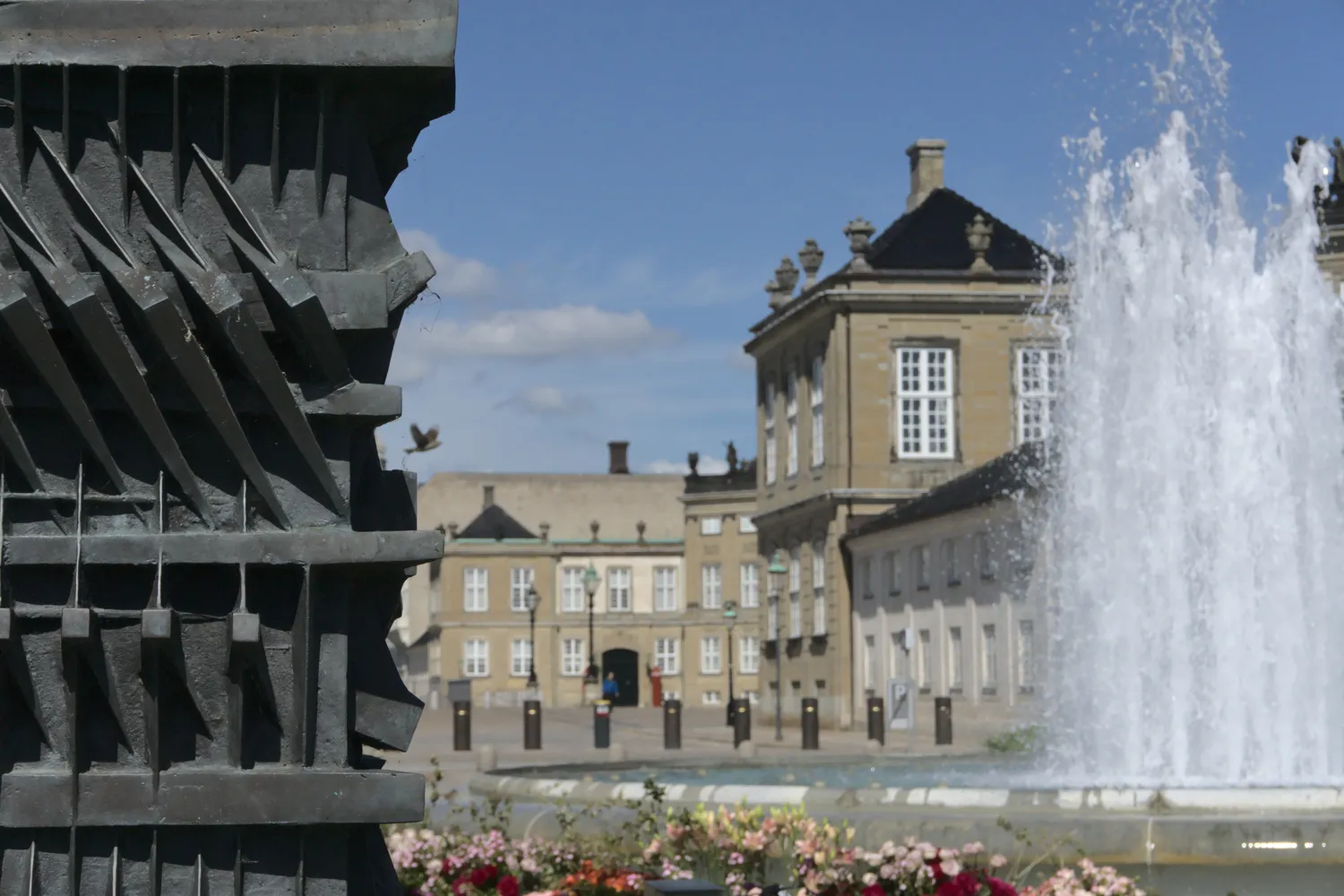 Dettaglio di scultura bronzea con palazzo e fontana zampillante sullo sfondo