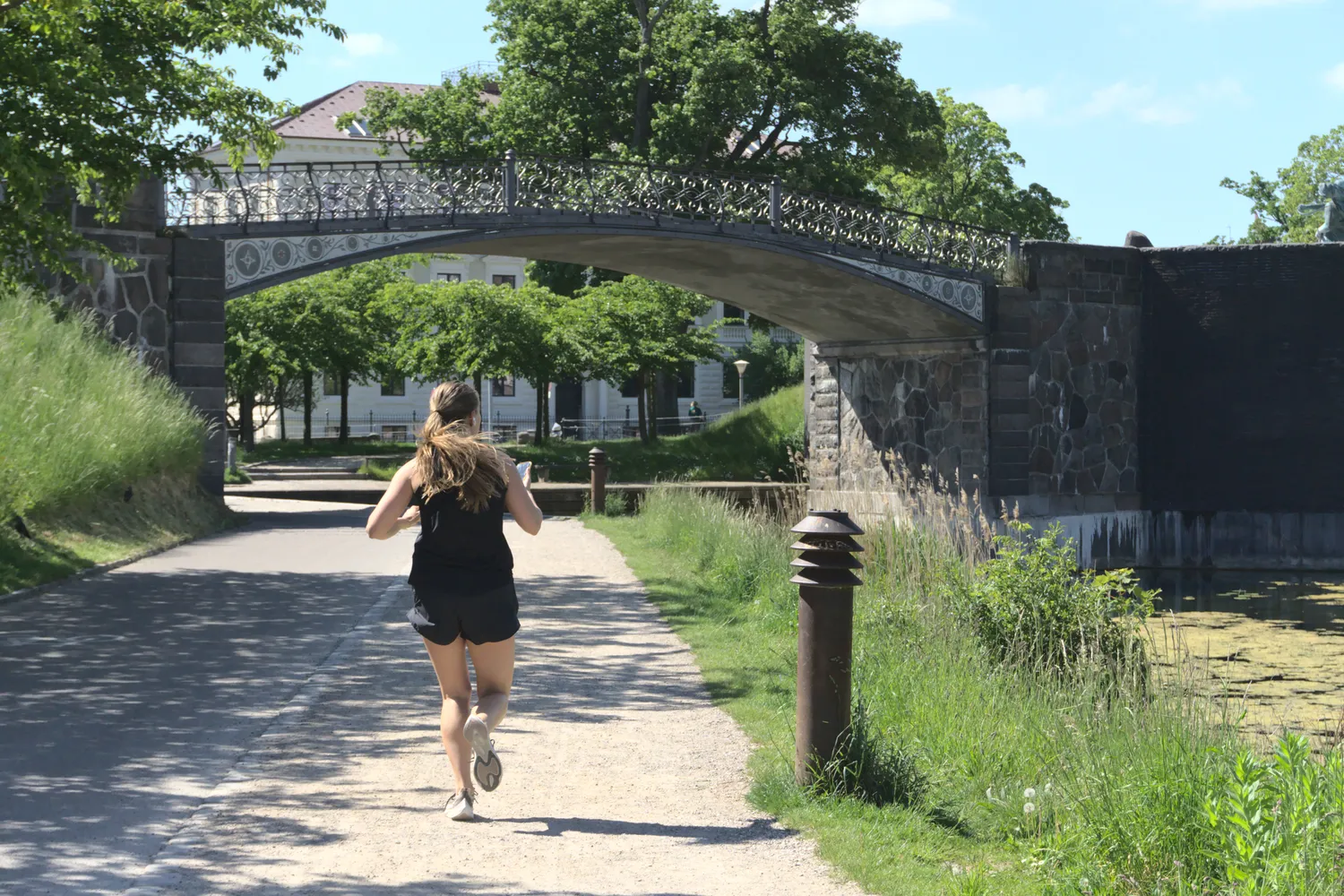 Donna che corre su un sentiero verso un ponte pedonale in ferro