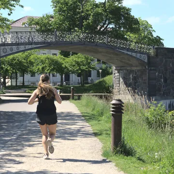 Donna che corre su un sentiero verso un ponte pedonale in ferro