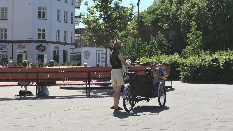 Donna ferma in piazza con una bici cargo e bambini a bordo