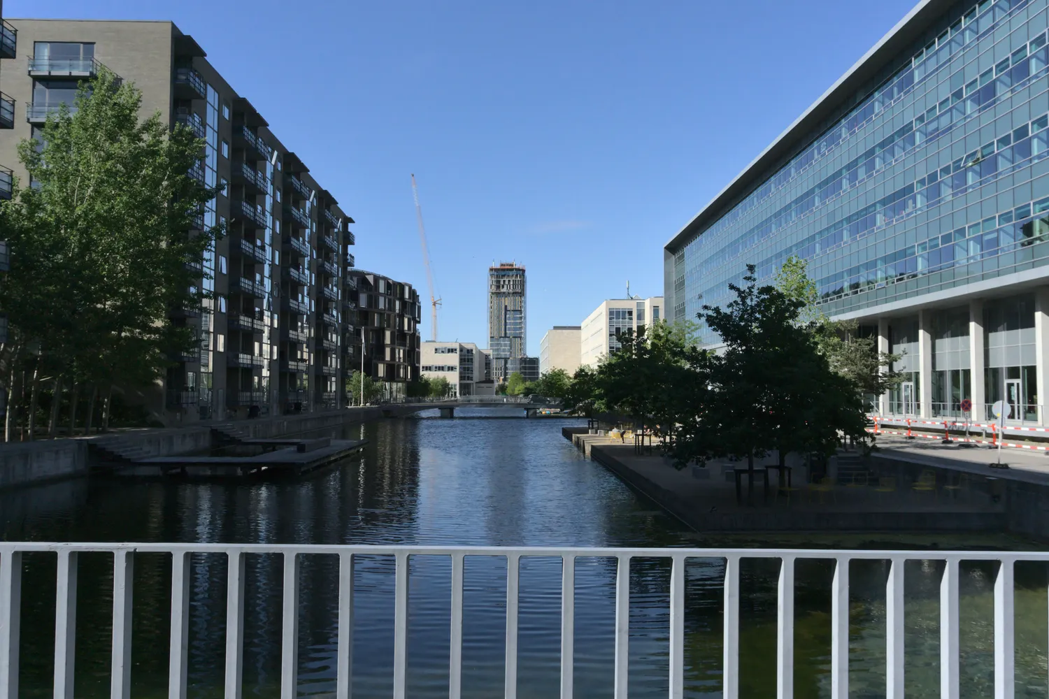 Canale tra moderni edifici del quartiere Ørestad, con gru in lontananza