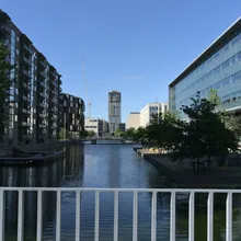 Canale tra moderni edifici del quartiere Ørestad, con gru in lontananza