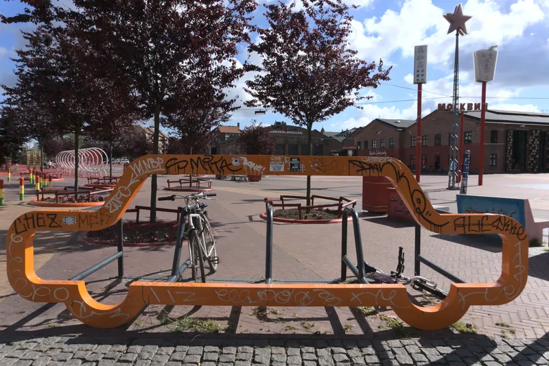 Rastrelliera per biciclette arancione a forma di mensola in una piazza