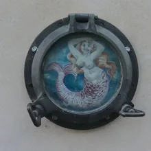 Oblò di nave su muro con dipinta una sirena dai capelli rossi
