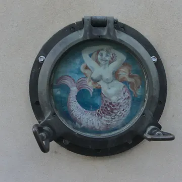 Oblò di nave su muro con dipinta una sirena dai capelli rossi
