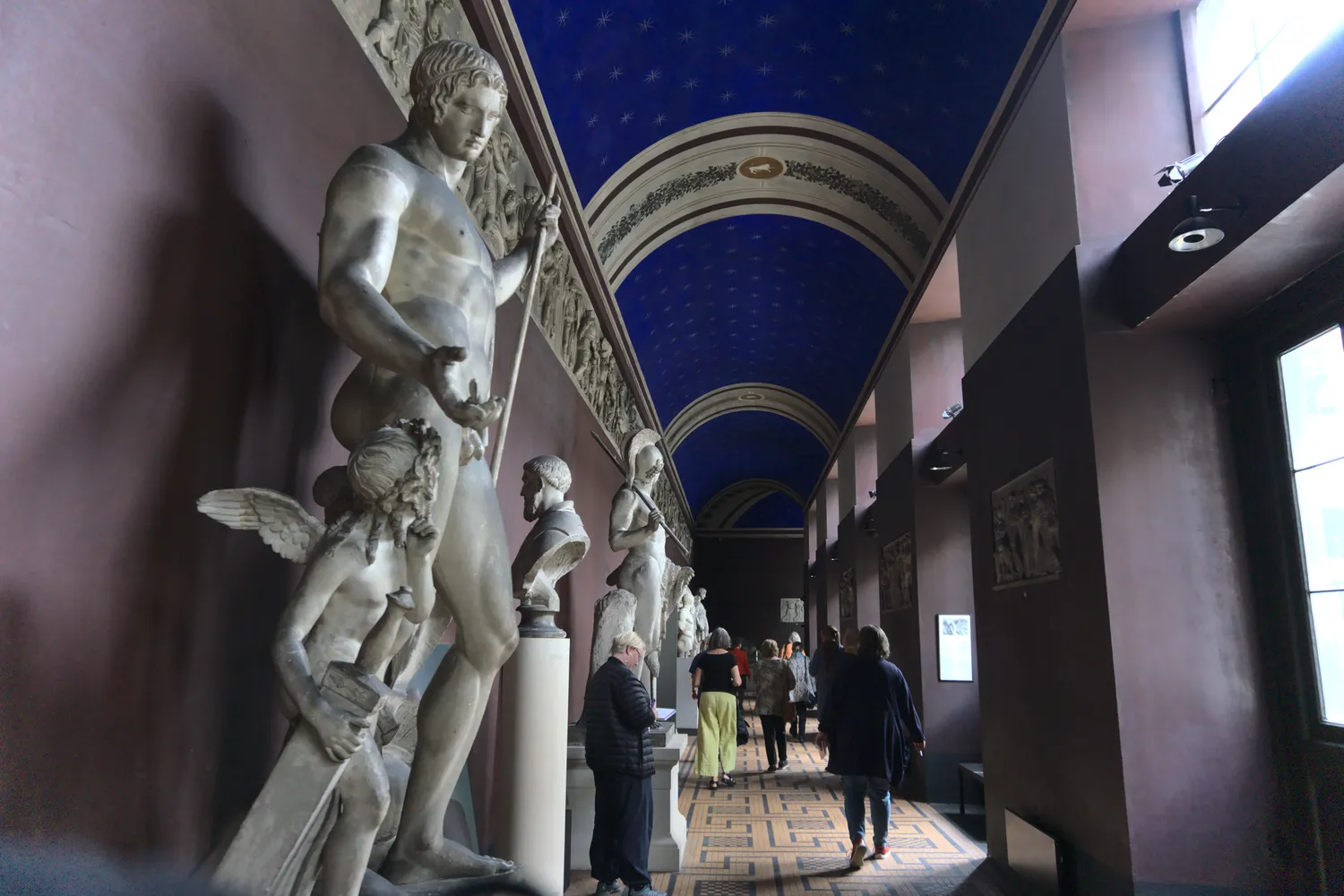 Galleria di sculture classiche in gesso sotto un soffitto blu stellato