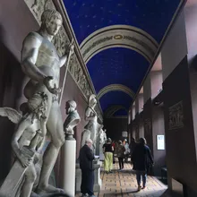 Galleria di sculture classiche in gesso sotto un soffitto blu stellato