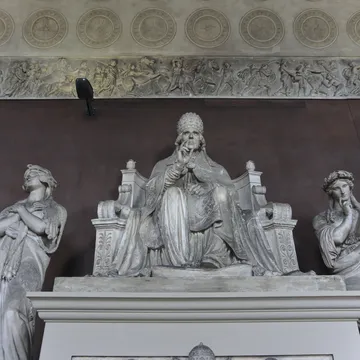 Scultura di un papa seduto in trono affiancato da figure femminili