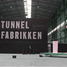 Capannone industriale con grande scritta Tunnel Fabrikken su container neri