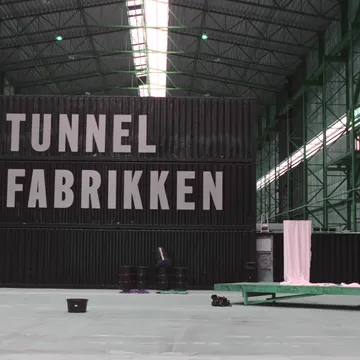 Capannone industriale con grande scritta Tunnel Fabrikken su container neri