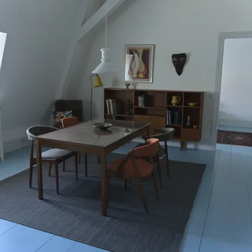 Sala da pranzo in stile danese con tavolo e sedie in teak su pavimento azzurro