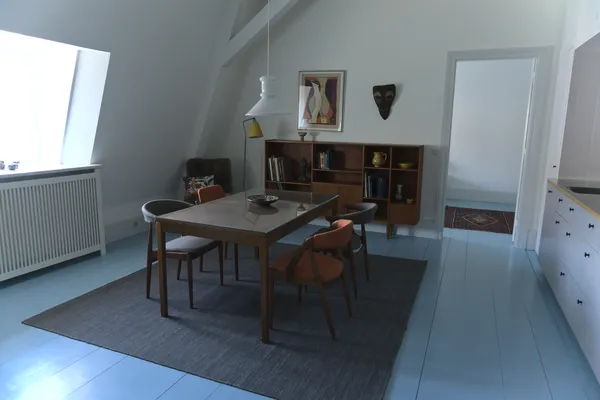 Sala da pranzo in stile danese con tavolo e sedie in teak su pavimento azzurro