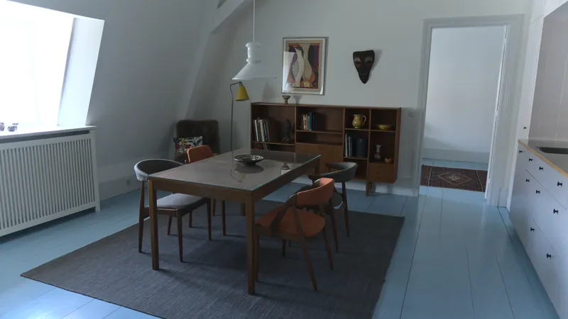 Sala da pranzo in stile danese con tavolo e sedie in teak su pavimento azzurro