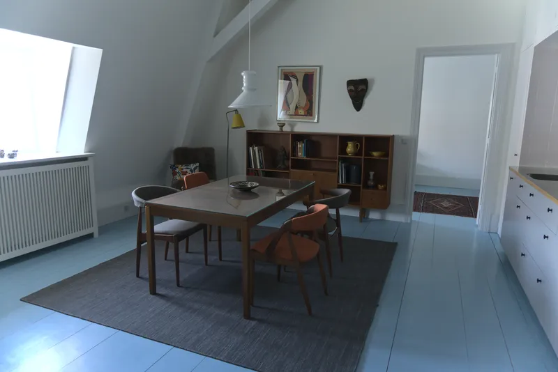 Sala da pranzo in stile danese con tavolo e sedie in teak su pavimento azzurro