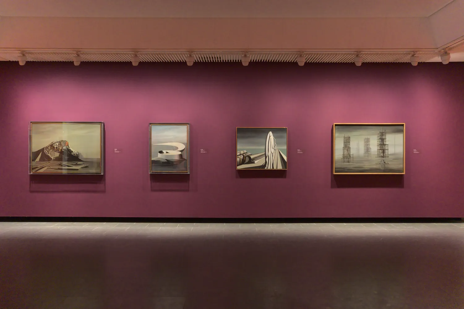 Quattro dipinti surrealisti incorniciati su parete magenta al Louisiana Museum of Modern Art