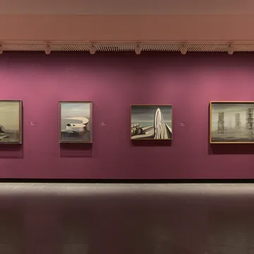 Quattro dipinti surrealisti incorniciati su parete magenta al Louisiana Museum of Modern Art