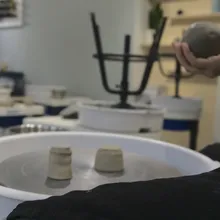 Tornio da ceramica con piccoli vasi e mano che impasta una palla di argilla