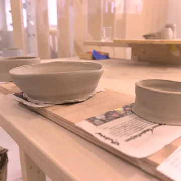 Ciotole di argilla grigia non cotta su tavole di legno in uno studio di ceramica