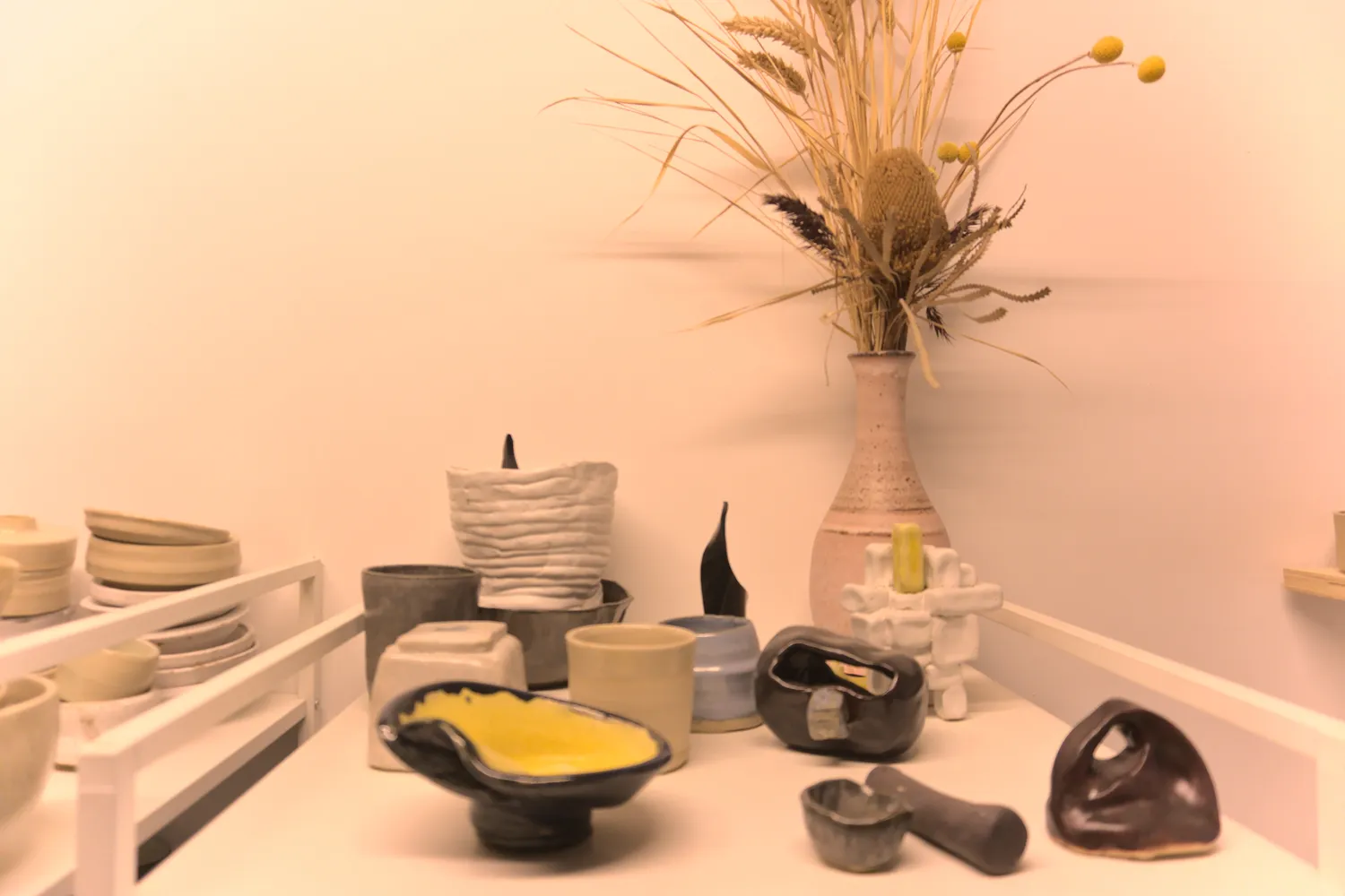 Composizione di ceramiche fatte a mano accanto a un vaso con fiori secchi