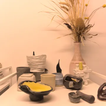 Composizione di ceramiche fatte a mano accanto a un vaso con fiori secchi