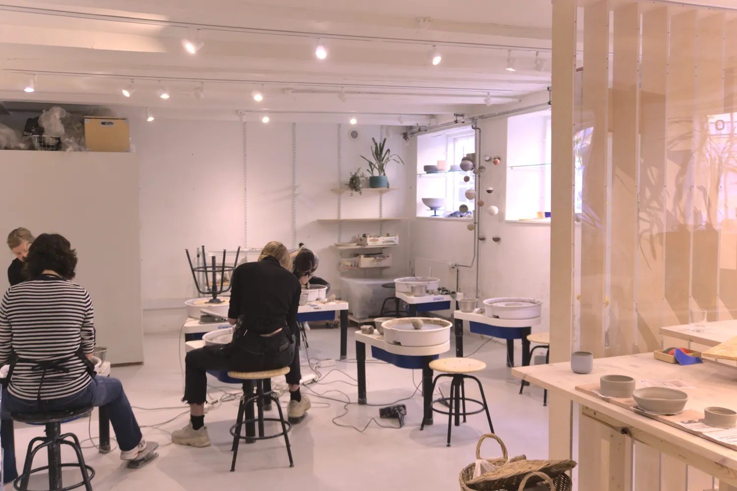 Persone modellano ceramica al tornio in un laboratorio luminoso