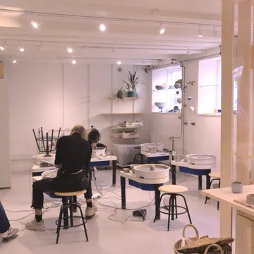 Persone modellano ceramica al tornio in un laboratorio luminoso
