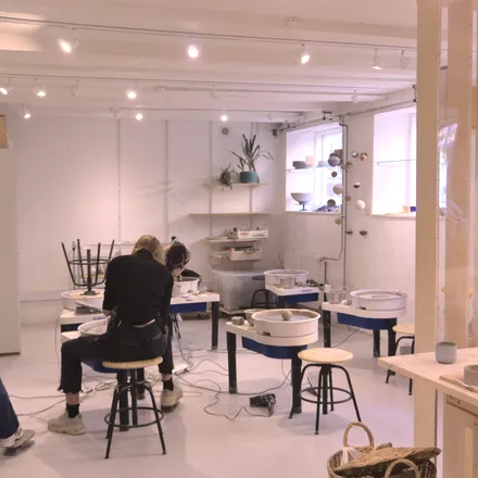 Persone modellano ceramica al tornio in un laboratorio luminoso